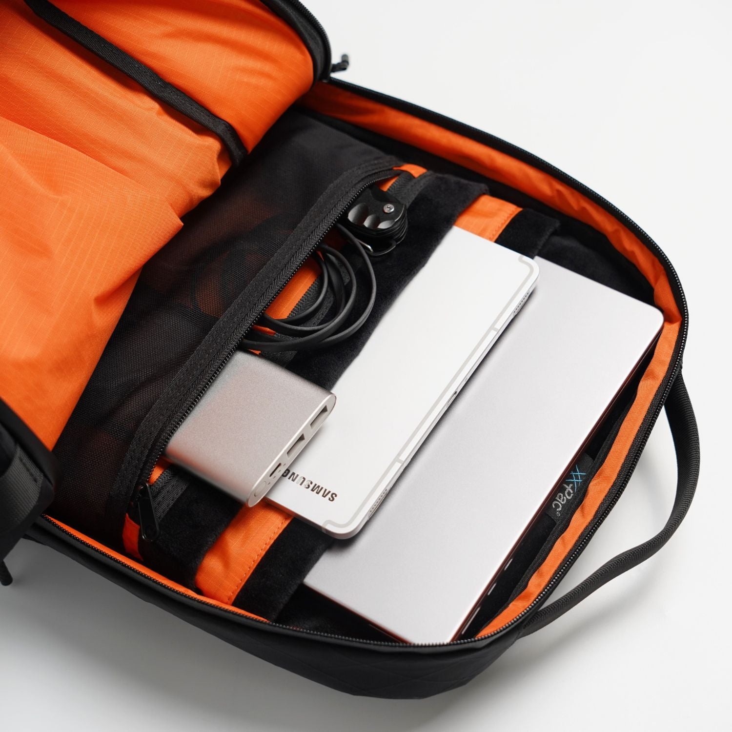 Open main compartment of ADD1D D2D Essential Backpack showing 15.6-inch laptop sleeve and high-vis orange lining