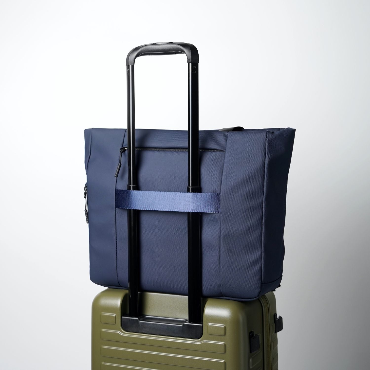 Rear luggage handle pass-through strap on ADD1D Kangaroo Messenger Tote secured on a rolling suitcase