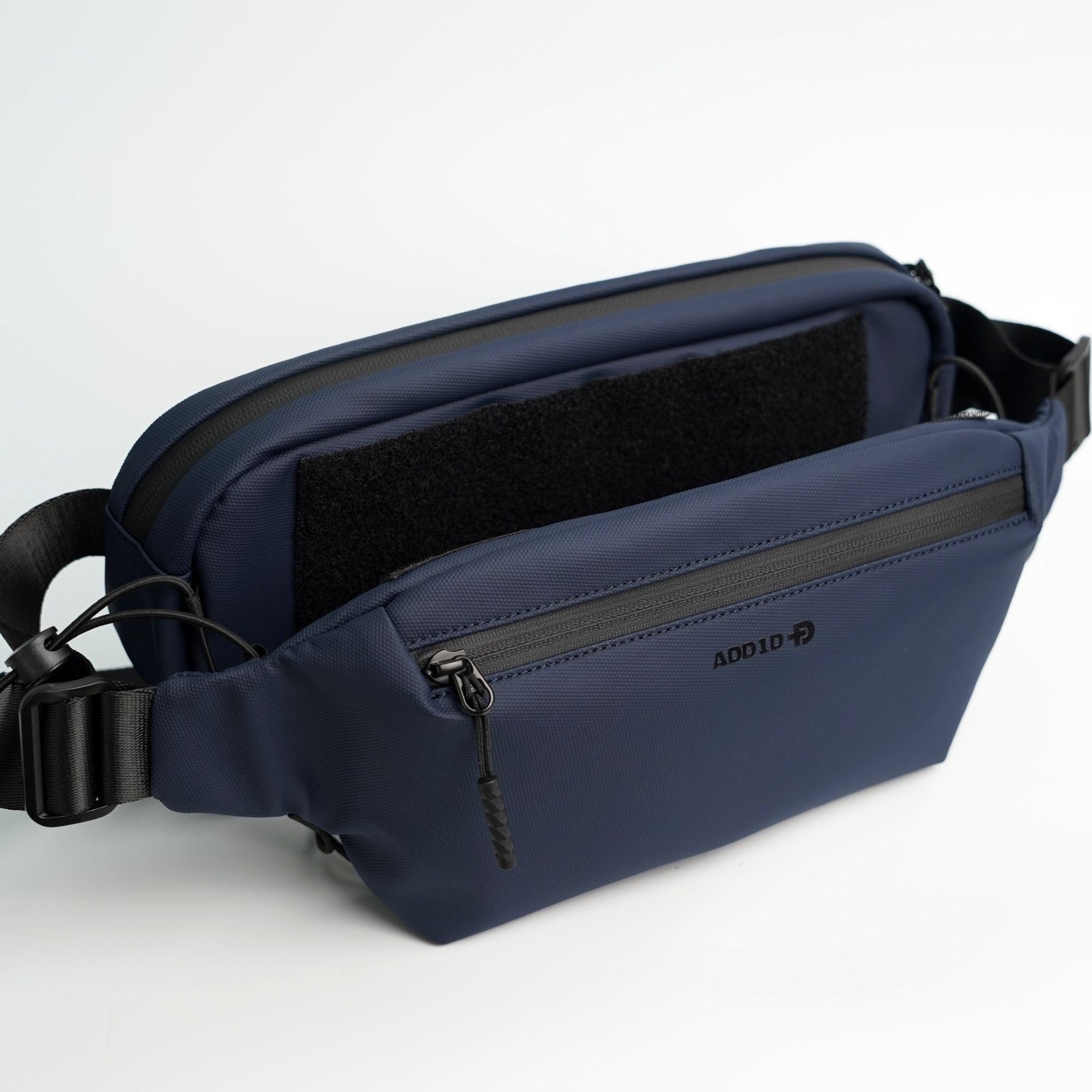 Expandable Kangaroo Pocket on ADD1D sling bag holding a jacket and water bottle